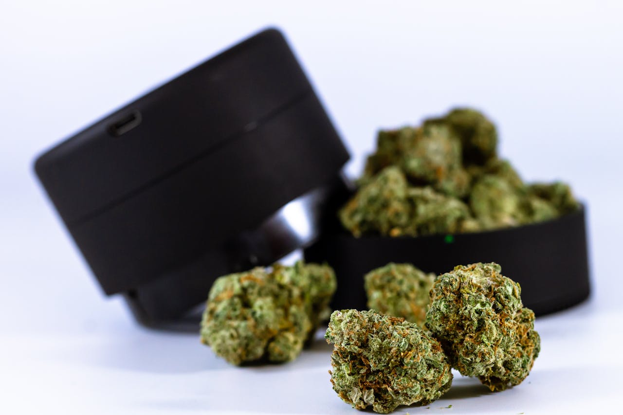 Close-up of cannabis buds with a black grinder, showcasing their texture and color.